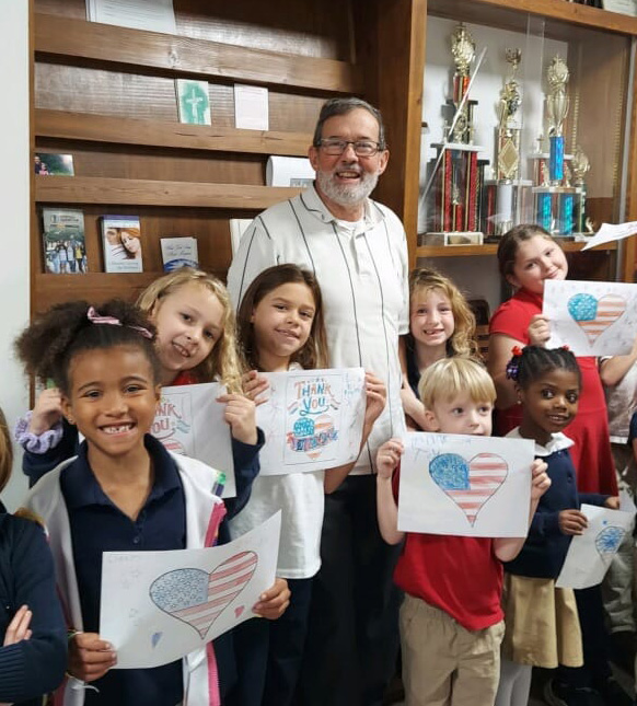 Administrator and students hold up patriotic artwork