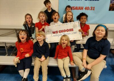 Students sit on risers with sign that says, "We Choose Countryside"