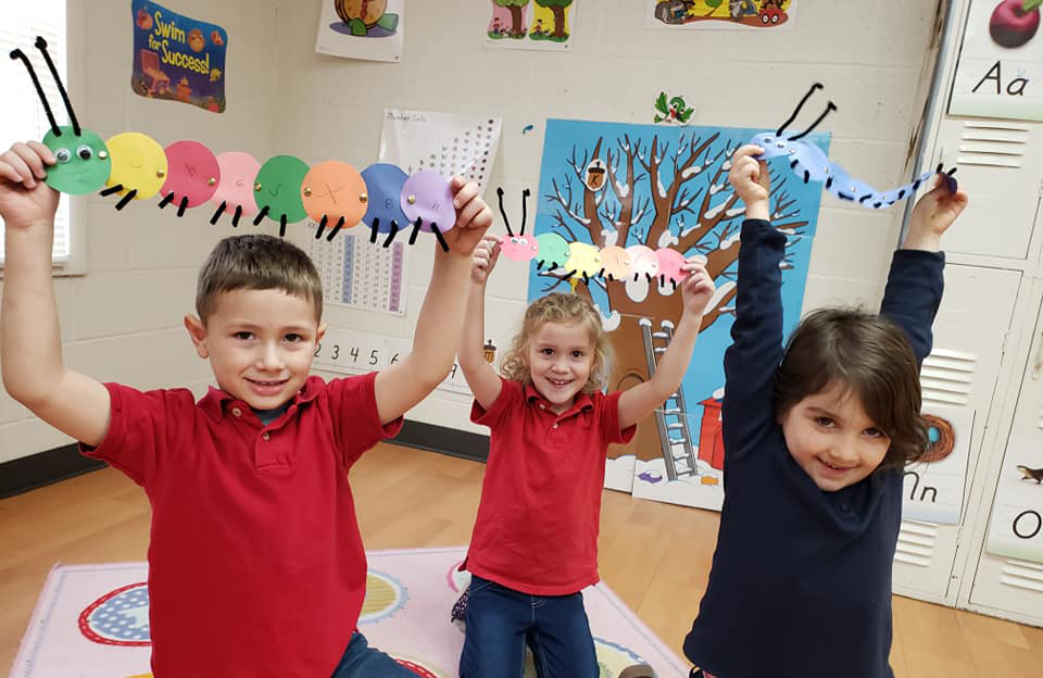 3 students holding up their caterpillar creations